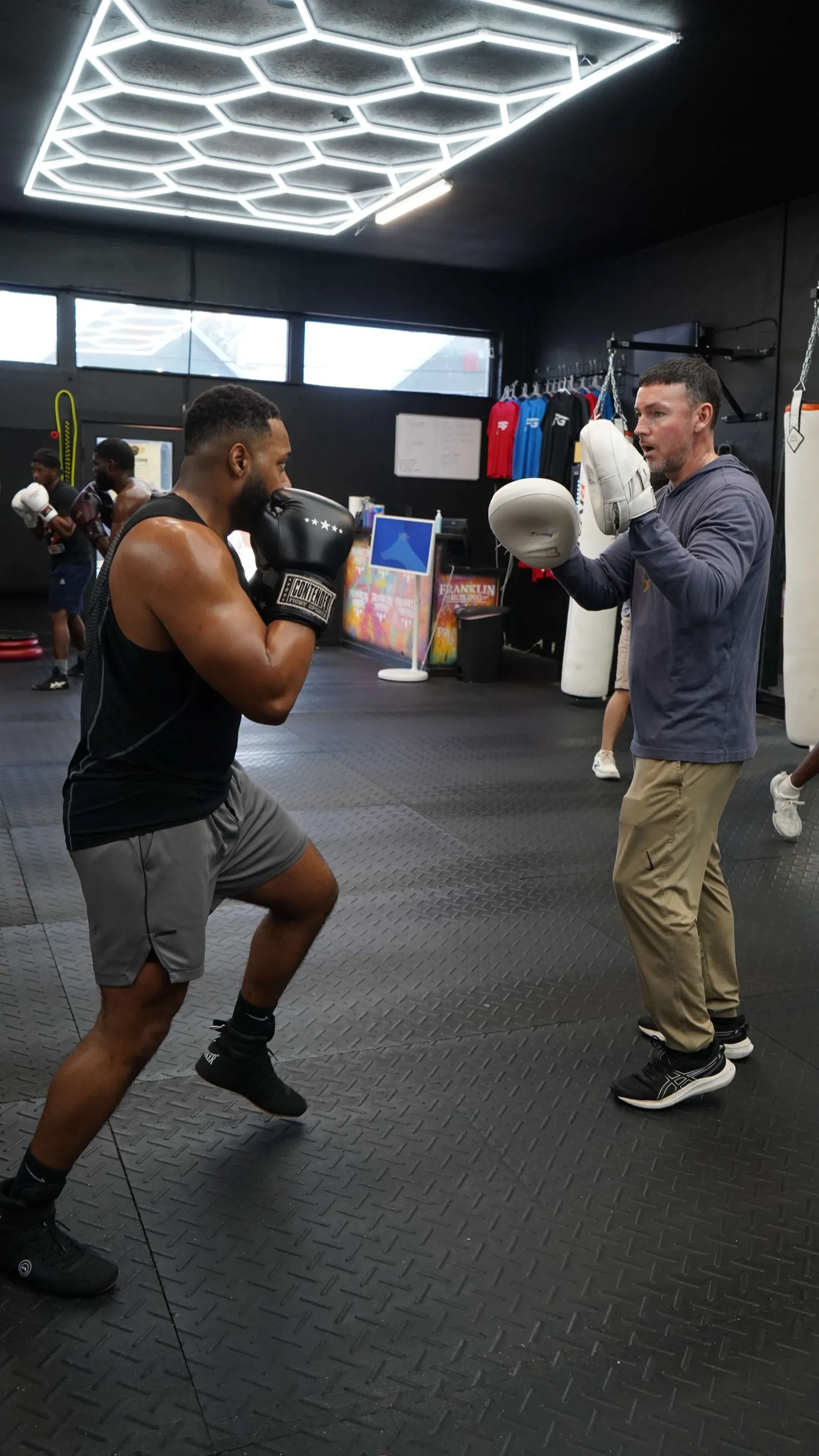 Members sparring under hexagon lights at Franklin Gym
